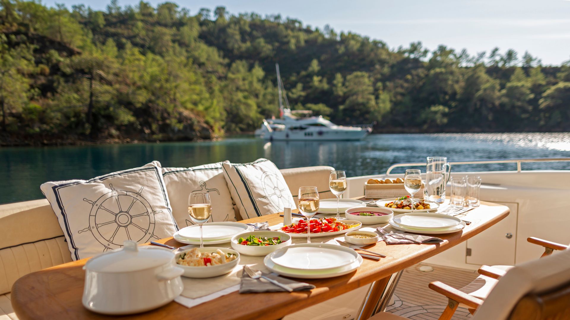 Executives collaborating around a large wooden table on the shaded aft deck of a private yacht sailing in Croatia