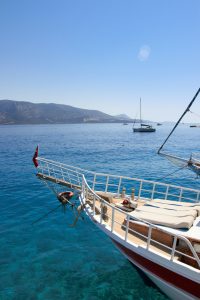Bow of a classic sailing yacht along a coastline