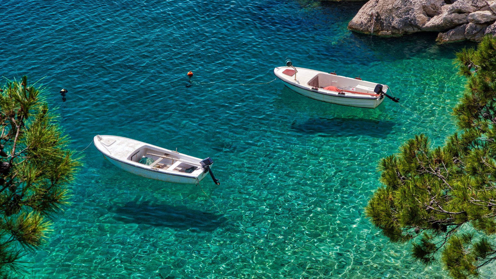 Hvar Island Croatia from the water — terracotta rooftops, lavender fields, and a private yacht anchored in the harbor — Sirena Collective luxury travel