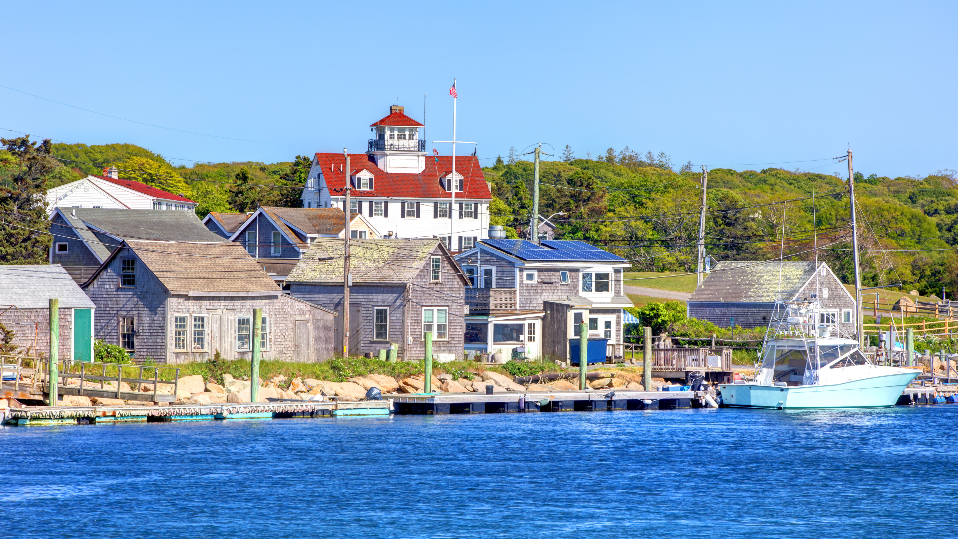 Menemsha fishing village Martha's Vineyard with shingled buildings boats and lighthouse — Sirena Collective