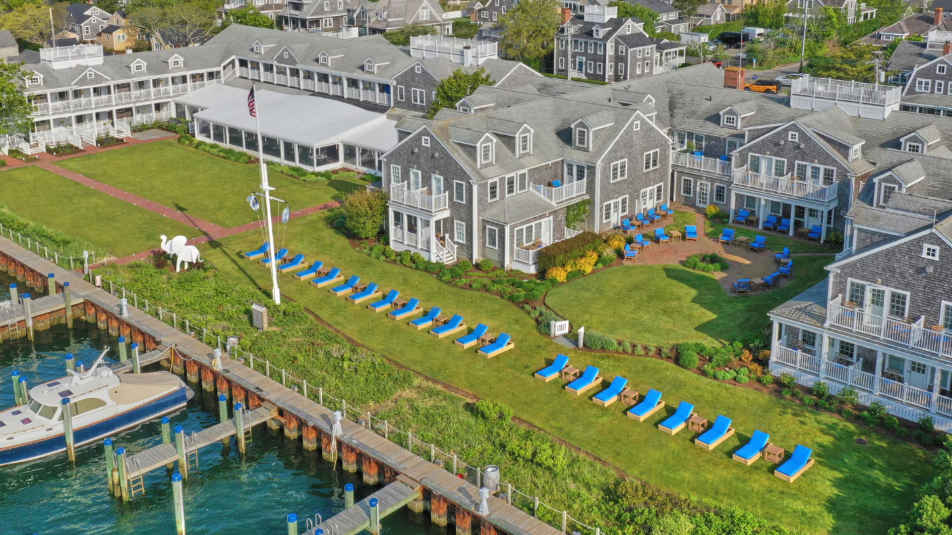 Aerial view of White Elephant Hotel Nantucket with blue lounge chairs on harbor lawn — Sirena Collective