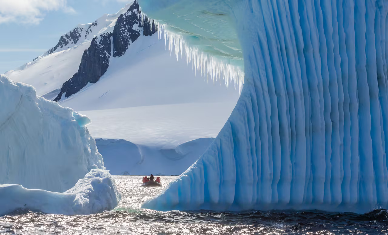 Lindblad Expeditions Zodiac negotiating massive sapphire iceberg in Dorian Bay Antarctica