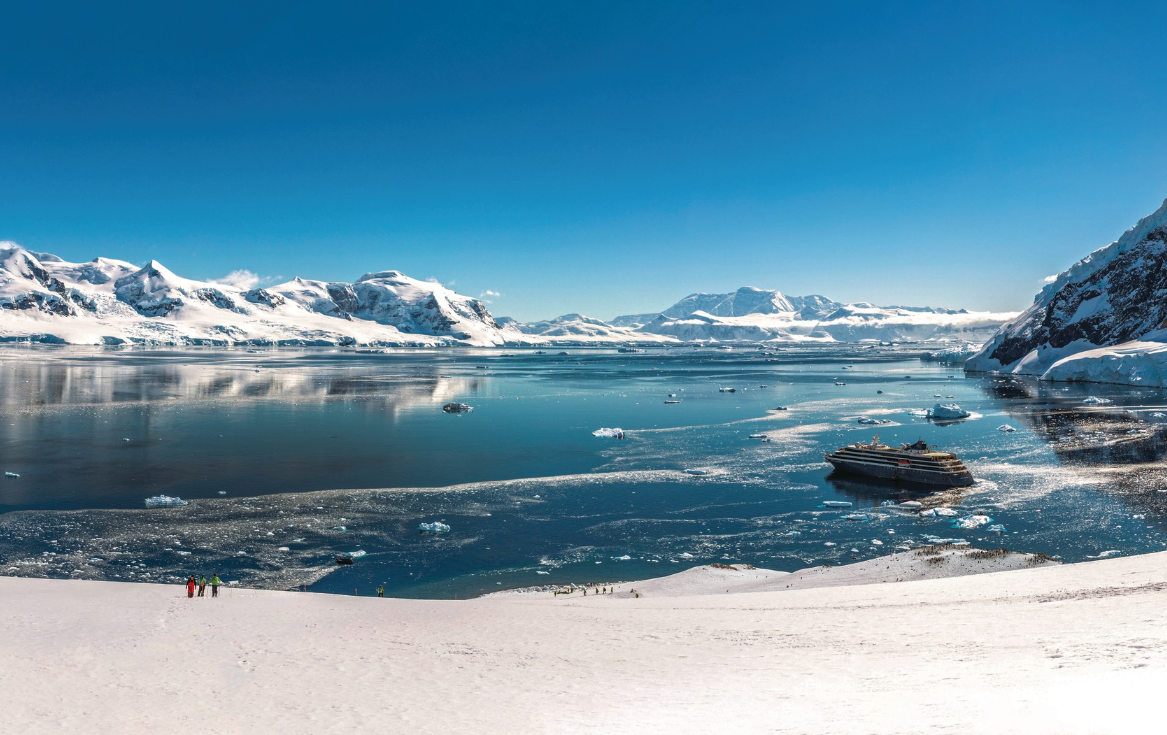 Atlas Ocean Voyages luxury expedition yacht anchored in Antarctic glacial fjord